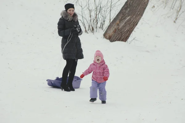 Moeder zijn ongehoorzame dochter in slee zitje op winter straat — Stockfoto