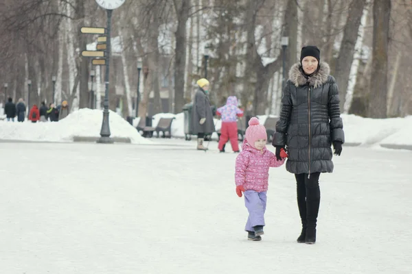 Schattig meisje wandelen in de sneeuw voor een wandeling met haar moeder — Stockfoto