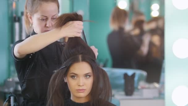 Maquilleur dans le salon de beauté rend la coiffure pour fille attrayante, gros plan — Video