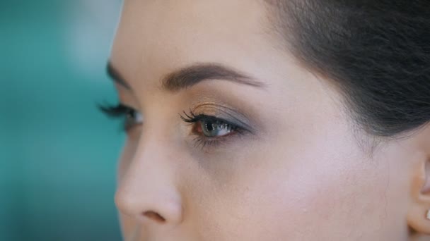 Ung brunett i en skönhetssalong, makeup-artist gör makeup och konturering, frisören gör styling - makro skott — Stockvideo