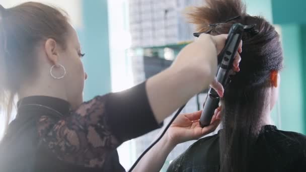 Візажист, перукар, що працює з клієнтом в салоні краси, розчісує волосся - вид ззаду — стокове відео