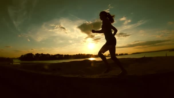 Young attractive woman is running in park at sunset, slow-motion, silhouette — Stock Video