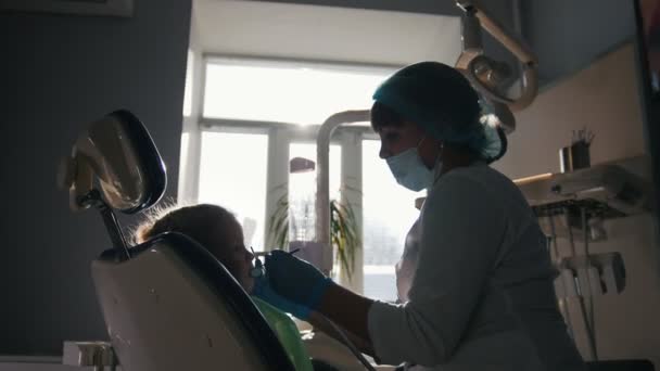 Fille à la réception chez le dentiste, la stomatologue examine les dents des enfants — Video