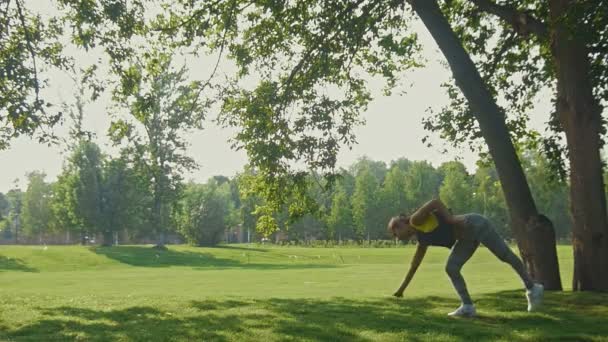 Entrenamiento: Joven atractiva hembra fitness haciendo elemento acrobático en el parque en la mañana de verano, cámara lenta — Vídeo de stock