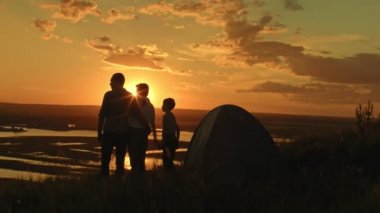 -Baba, anne ve oğul kamp içinde - genç mutlu sağlıklı aile yaz günbatımı ve horizont için arıyorum yüksek tepede duruyor