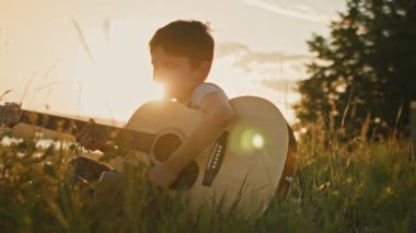 Çocuk çocuk yaz gün batımı çayır gitar çalmayı eğitim yaz alanında