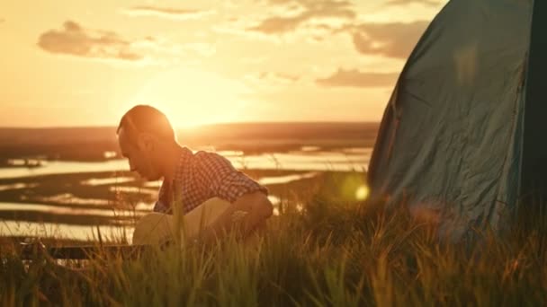 Homme tunes guitare acoustique dans le camping en plein air sur prairie au coucher du soleil d'été — Video