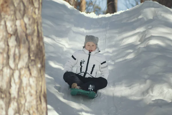 Маленька красива дівчинка-підліток катається в зимовому сонячному лісі — стокове фото