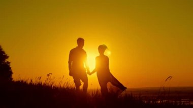 Çift - genç ve güzel kız gün batımı çayır yürüyüş - sevmek siluet