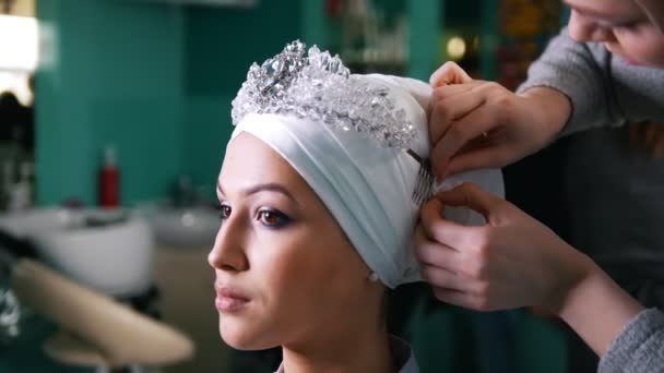 Женщина связывает исламский свадебный тюрбан для красивой модели — стоковое видео