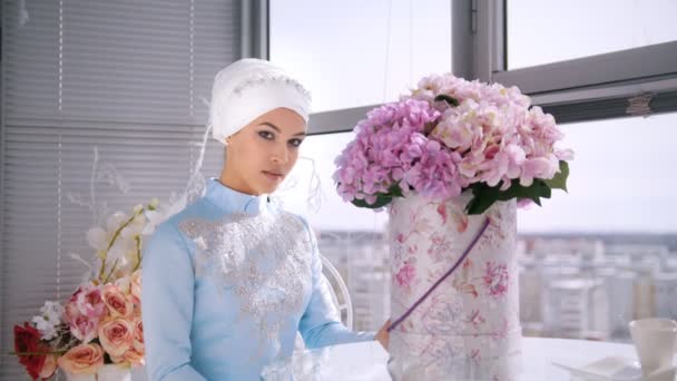 Hermosa novia musulmana con maquillaje en vestido tradicional azul para nikah sentado cerca de la ventana — Vídeos de Stock