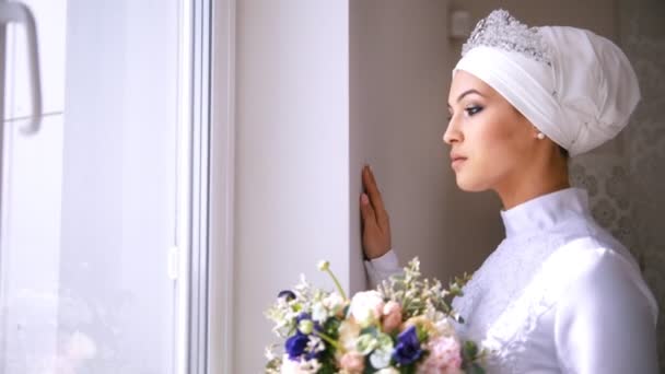 Schöne muslimische Braut mit Make-up schaut aus dem Fenster und lächelt — Stockvideo