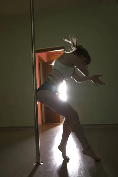 Mooie vrouw danser van de pool in strakke kleding met sexy vorm is dansen op de paal — Stockfoto