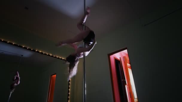 Aantrekkelijke vrouw spinnen op een paal in een studio — Stockvideo