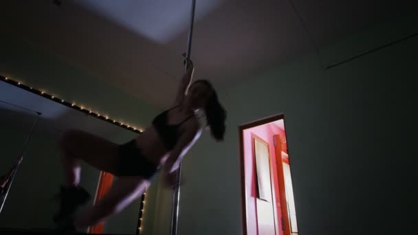 Flexible woman with long hair exercising pole dance in a studio — Stock Video