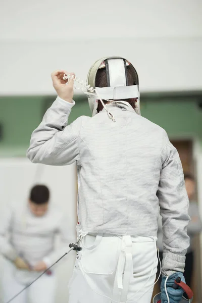 Achterkant van jonge Schermer in witte kostuum en beschermend masker — Stockfoto