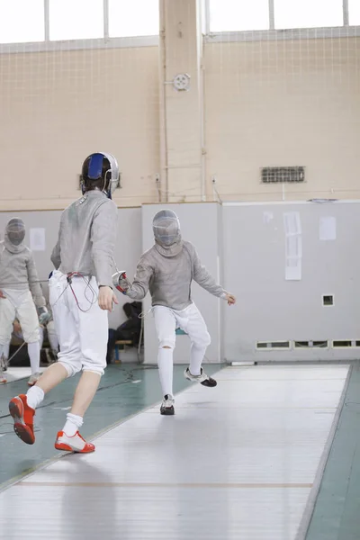 Молоді учасники турніру фехтування борються в захисному білому одязі — стокове фото
