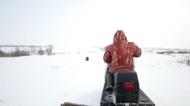 Hombre conduciendo moto de nieve en el campo cubierto de nieve — Vídeo de stock
