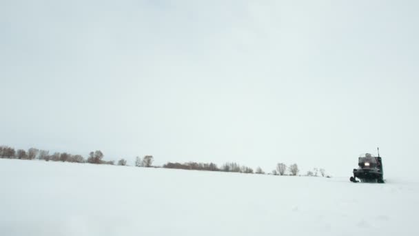Schneemobil mit Kutsche fährt durch das verschneite Feld — Stockvideo