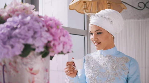 Beautiful muslim model in blue wedding dress drinking coffee
