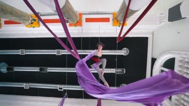 Genç kadın hava jimnastikçi asmak baş aşağı ve hava ipek sallayarak