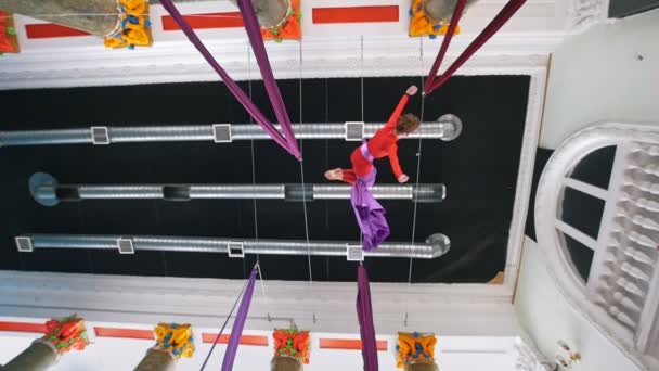 Beautiful woman air gymnast hangs upside down on the aerial silk — Stock Video
