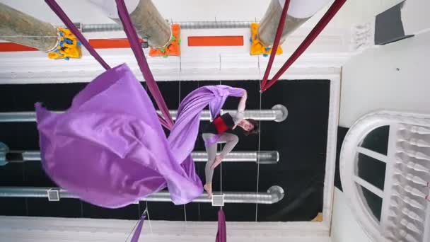 Attractive girl air gymnast hangs upside down and waving the aerial silk — Stock Video