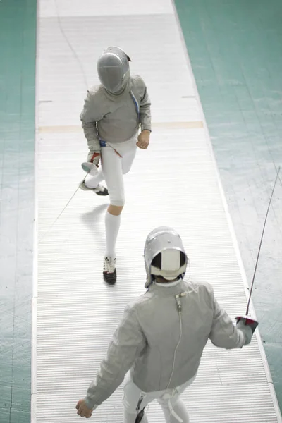 Zwei junge Kämpfer in Schutzmaske kämpfen beim Fechtwettbewerb — Stockfoto