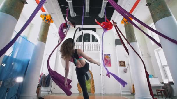 Belles femmes souples qui tournent autour du cerceau aérien et de la soie dans un studio — Video
