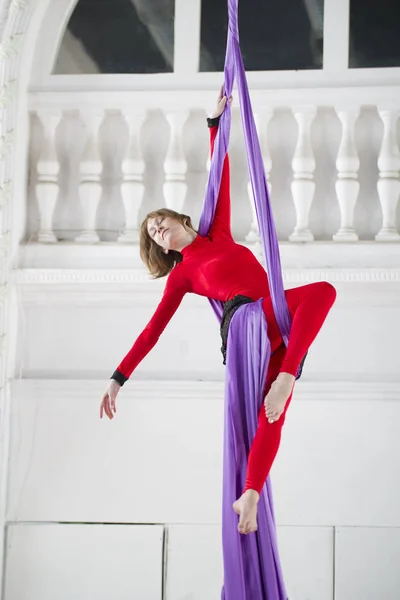 Young woman doing gymnastics on aerial silk