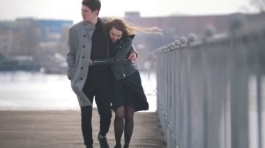 Genç Beyaz adam ve yürüyen kadın rüzgarlı bir günde sarıldı