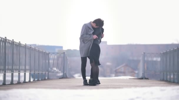 Молодой кавказский мужчина и женщина ходят обнимаясь в ветреный день — стоковое видео