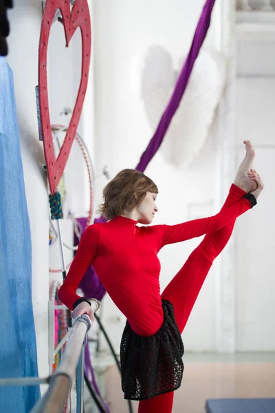 Elegante gimnasta haciendo estiramiento con barra en un estudio —  Fotos de Stock
