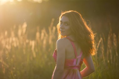 Gün batımında çayırda güzel bir genç kadın portresi