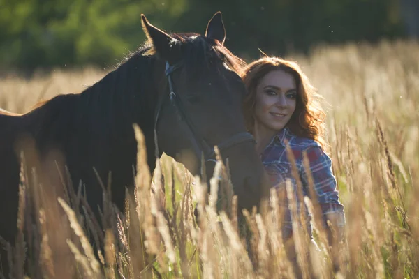 Retrato de uma jovem mulher e cavalo no prado à noite de verão — Fotografia de Stock