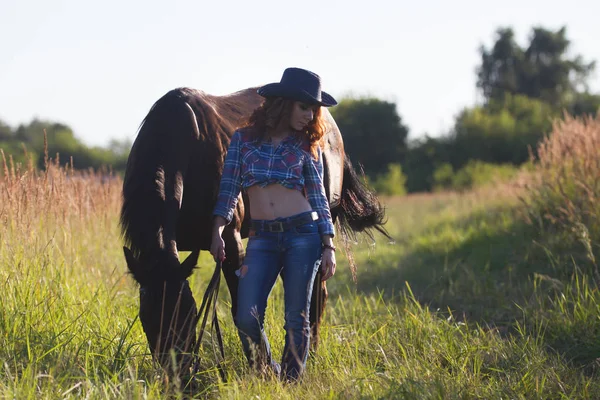 Портрет ковбойши - молодая женщина с лошадью на лугу в летний день — стоковое фото
