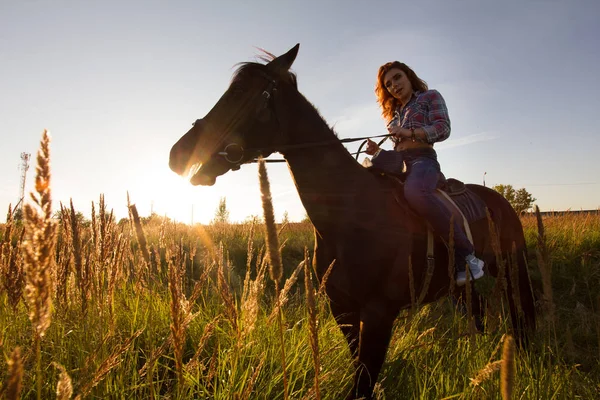 Silueta de una mujer montada a caballo - puesta de sol o salida del sol, horizontal — Foto de Stock