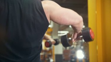Arkadan görünüş kaslı adamın bir dumbbell bir spor salonunda kaldırdı.