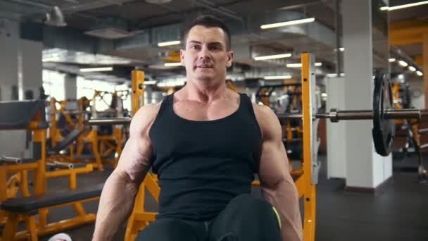 Homem forte atlético levanta um halteres em um ginásio brilhante — Vídeo de Stock