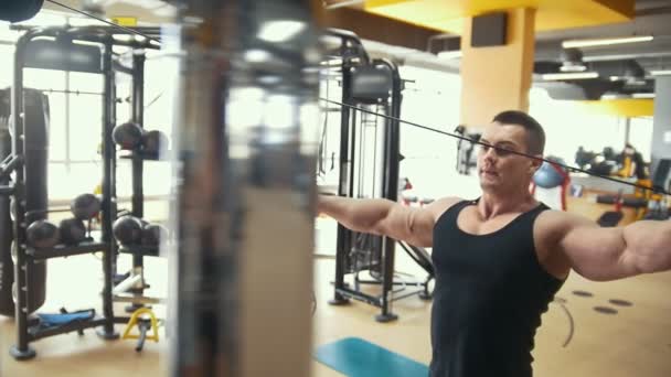 Hombre atlético joven haciendo ejercicios de fuerza en una sala de ejercicios — Vídeo de stock