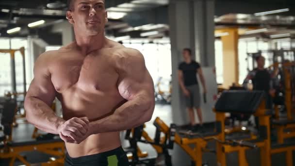 Сильный бодибилдер без рубашки с обнаженным мускулистым туловищем в тренировочной комнате — стоковое видео