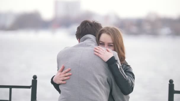 Молодая пара обнимается на заднем плане на берегу реки — стоковое видео