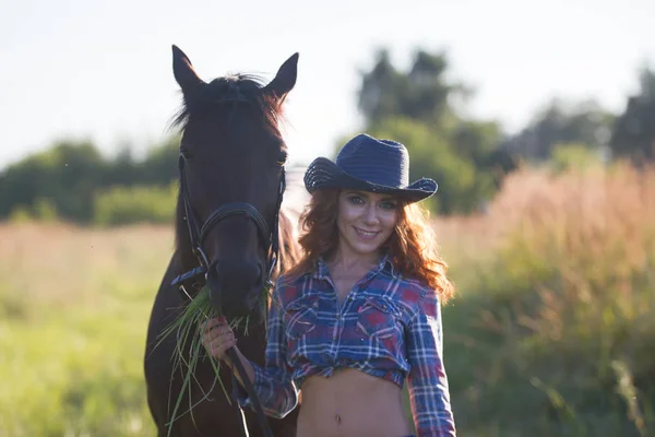 Porträt eines Cowgirls - junge Frau mit Pferd auf der Weide an einem Sommertag — Stockfoto