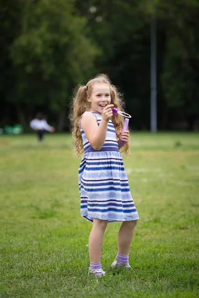 Bonita niña rubia sonriente con chaqueta vaquera en el parque — Foto de Stock