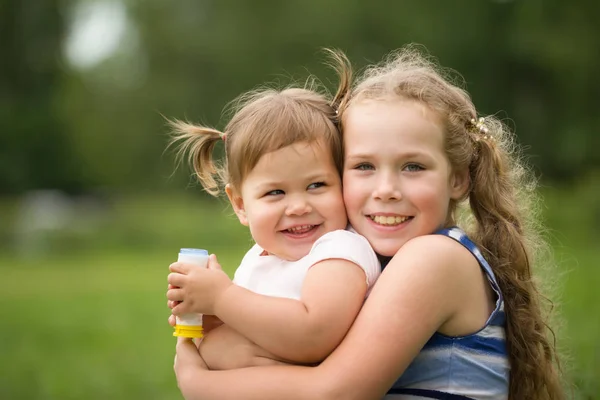 Happy little sisters - portrét v parku — Stock fotografie