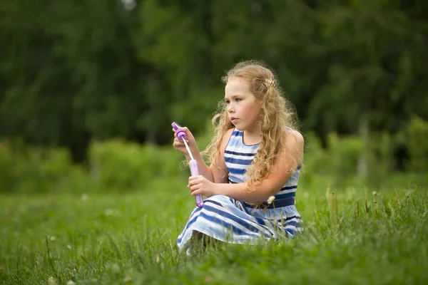 夏のドレスを着て笑顔のかなり金髪の子供が公園で遊んでは — ストック写真
