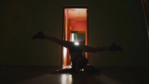 Silhouette dancing woman in tight-fitting clothes in the dark room