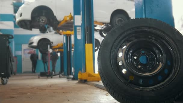 Автомобиль в автосервисе подъем для ремонта, механика в гараже — стоковое видео