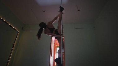 Seksi siyah saçlı kız direk dansör bir stüdyoda eğitim