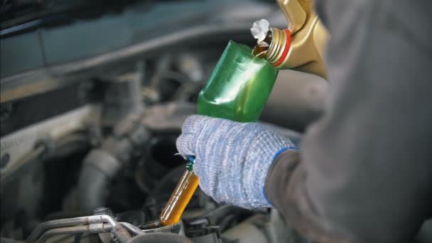 Механик в перчатках заливает моторное масло в двигатель автомобиля — стоковое видео